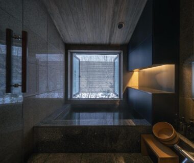 Indoor stone soaking tub with wooden stool and bucket, framed window view at OTARU RETREAT in Hokkaidō