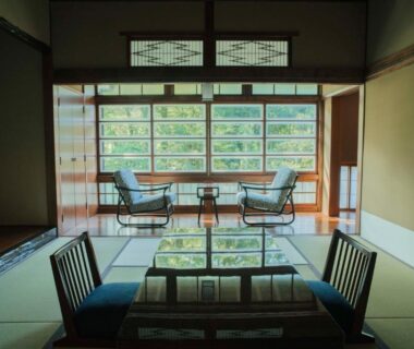 Tatami room with low table, floor chairs and seating by window overlooking green foliage