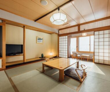 Traditional tatami room with low table, zabuton cushions, shoji screens and window seating at Oehonke in Hokkaidō