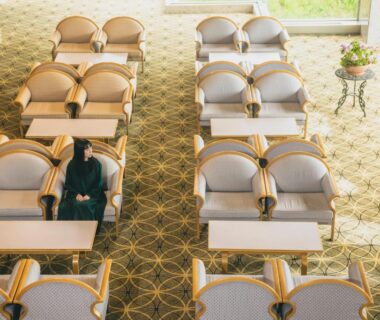 Overhead view of arranged upholstered chairs and small tables in Oehonke lounge, bright carpeted seating area in Hokkaidō Japan