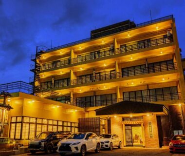 Exterior of Ogiwarakan at dusk with illuminated facade and parked cars in Nagano Chūbu