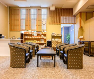 Ryokan lobby with armchairs, low tables, wooden reception counter and shoji-style windows