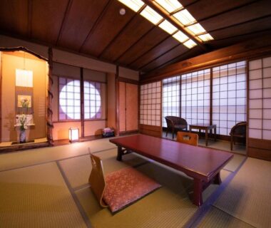 Spacious tatami room with low table, zabuton cushions, shoji screens and tokonoma alcove at Ohanabo Kyoto