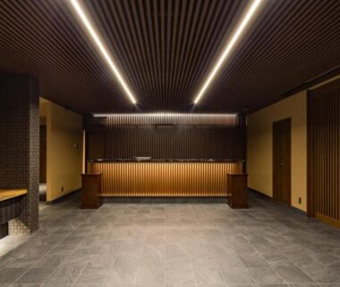 Modern reception lobby with bonsai, wooden slats and stone floor at Oike Hotel in Yamanashi
