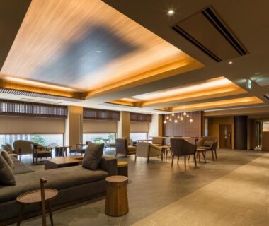Spacious warm-lit lobby with sofas, wooden accents and low tables at Oike Hotel in Yamanashi