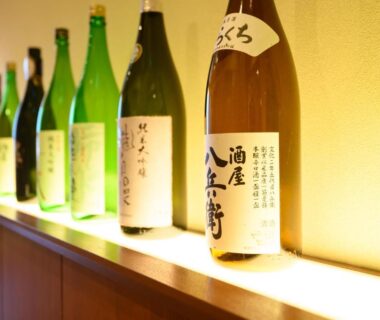 Backlit row of sake bottles displayed on a shelf at Oishiya ryokan in Mie