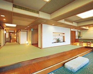 Wide tatami common room with raised wooden platform, shoji screens, seating cushion and decorative alcove at Oishiya in Mie
