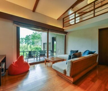 Spacious wooden-floored room with sofa and balcony at Oita Kuoritei in Ōita, Kyūshū, Japan