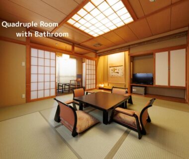 Traditional tatami room with low table, floor chairs, shoji screens and television at Oiwakeya Ryokan, Nagano