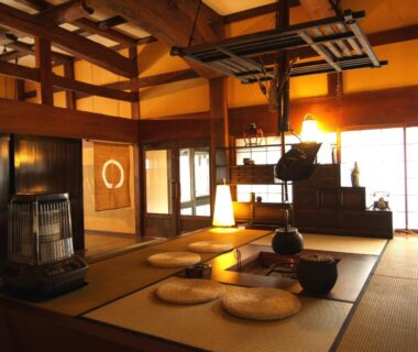 Tatami room with central irori hearth, zabuton cushions and wooden beams at Okada Ryokan Warakutei in Gifu