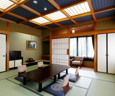Spacious tatami room with low dining table, floor cushions, shoji screens and window seating at Okada Ryokan Warakutei in Gifu