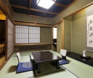 Traditional tatami room with low table, zabuton cushions, shoji screens and tokonoma at Okada Ryokan Warakutei Gifu