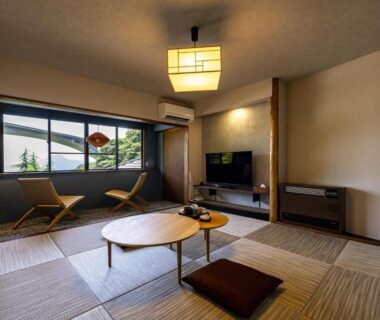 Tatami-style room with low round table, floor cushion and window chairs at Okamotoya, Ōita