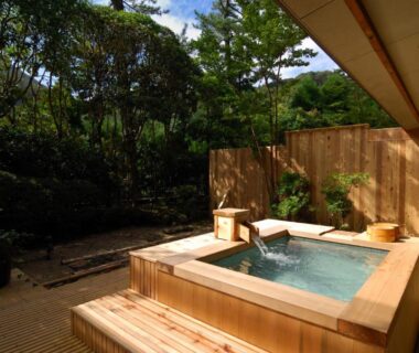 Wooden outdoor soaking tub on deck with garden greenery and wooden fence at Oku Yugawara SANSUIROU Kanagawa