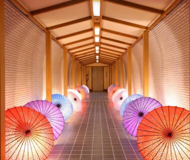 Illuminated umbrella-lined corridor at Oku Yugawara SANSUIROU in Kanagawa, traditional wooden beams and shoji-style walls