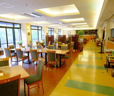 Bright ryokan dining area with wooden tables, upholstered chairs, large windows and dividers at Okuhida Garden Hotel Yakedake, Gifu
