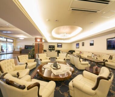 Spacious ryokan lounge with cream sofas, round coffee table, chandelier and reception area at Okuhida Garden Hotel Yakedake in Gifu
