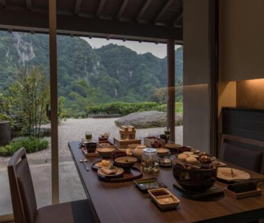 Table set with dishes by sliding doors overlooking garden and mountains at Okuhita Onsen Umehibiki in Ōita, Kyūshū