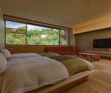 Spacious tatami room with twin beds and large window overlooking greenery at Okuhita Onsen Umehibiki, Oita