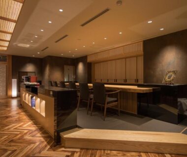 Warm wooden reception lounge with counter seating and parquet floor at Okuhita Onsen Umehibiki Oita