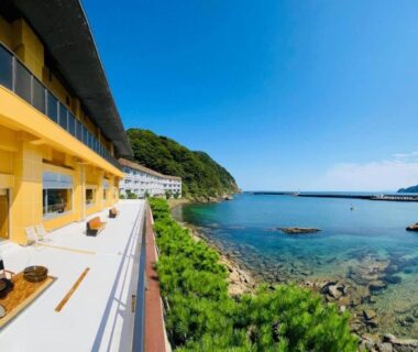 Balconies with chairs overlooking clear sea and rocky shoreline at Okukinosaki Seaside Hotel, Hyōgo