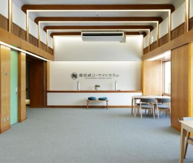 Spacious reception area with wooden beams, carpeted floor, seating and front desk at Okukinosaki Seaside Hotel, Hyōgo