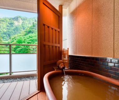 Wooden soaking tub on balcony overlooking green mountains at Okuno Hosomichi in Hyōgo Kansai