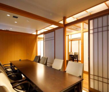 Long dining table with chairs, shoji screens and warm wood interior at Okuno Hosomichi, Hyōgo