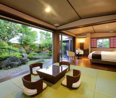 Tatami seating area and bed with open sliding doors to a landscaped garden at Okuyado Buaiso in Ōita