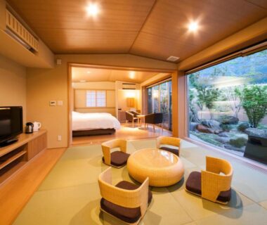 Tatami room with low seating, bed and garden view at Okuyado Buaiso, Ōita Kyūshū