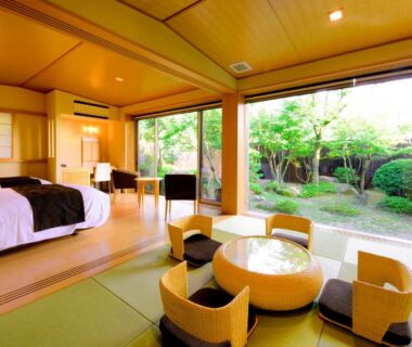 Tatami room with low table, western bed and garden view at Okuyado Buaiso, Ōita