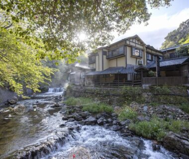 Riverside traditional ryokan Okyakuya beside a flowing mountain stream with trees in Kumamoto, Kyūshū