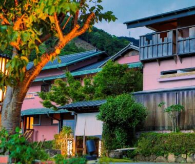 Traditional ryokan exterior with wooden balconies, lantern and landscaped greenery at Omoideno Jinde Chūbu Shizuoka