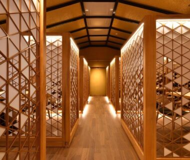 Warm wooden hallway with lattice screens and soft lighting inside Oni no Sumika ryokan in Shizuoka