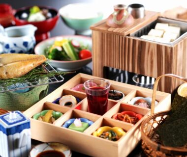 Bento-style breakfast set with grilled fish, assorted small dishes, pickles and tea on a ryokan table