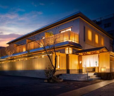 Lit traditional ryokan exterior at dusk with wooden facade and warm entrance, Onomichi Hansei, Chūgoku Hiroshima Japan