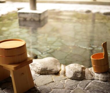 Stone-sided onsen with wooden stool and buckets at Onsen Guest House Tsutaya in Kanagawa, Japan