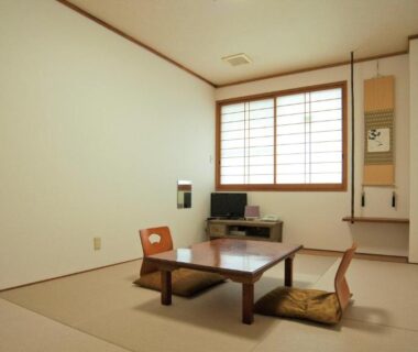 Simple tatami room with low table, floor cushions, shoji window and tokonoma at Onsen Urashima in Hiroshima