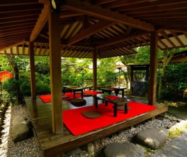 Open wooden garden pavilion with low tables and red cushions at Onsen Yado Mizuguchi, Shizuoka