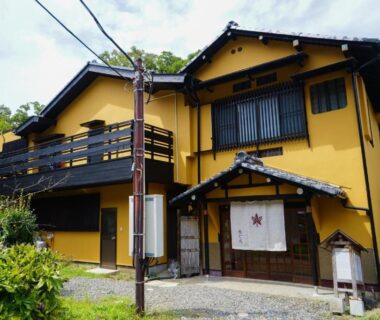Two-story yellow ryokan with noren curtain and wooden balcony, Onsen Yado Mizuguchi, Shizuoka