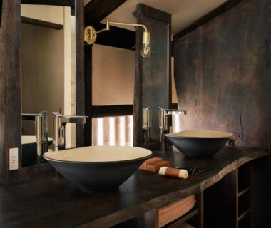 Two stone vessel sinks on dark wooden vanity with mirrors and metal faucets in ryokan washroom