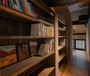 Narrow wooden hallway lined with bookshelves and shoji doors at the ryokan in Ishikawa