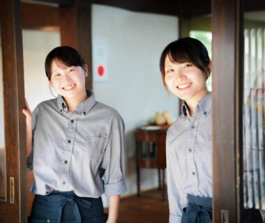 Two smiling staff greeting guests at ryokan entrance Onsen and Garden Nana Chūbu Ishikawa