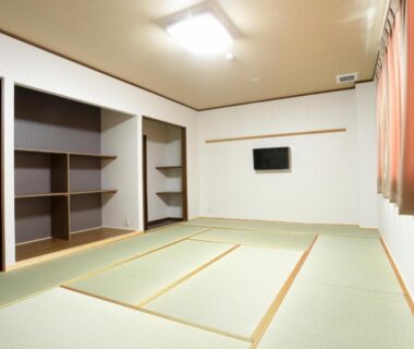 Tatami room with wall-mounted TV and open shelving at Onsenminshuku Kosakaya in Wakayama, Kansai
