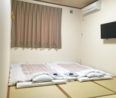 Simple tatami room with two futons, wall-mounted TV and air conditioner at Onsenminshuku Kosakaya in Wakayama
