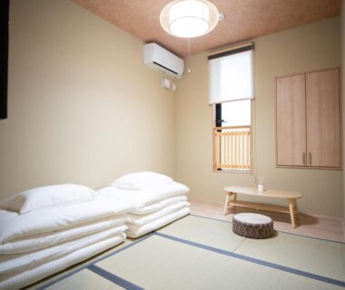 Minimal tatami room with folded futon, low table, shoji window and wall air conditioner at Onya Kaede Kyoto