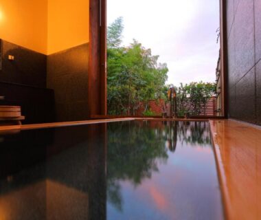 Wooden indoor bath at Onyado Satsuki opening to a small garden in Kumamoto