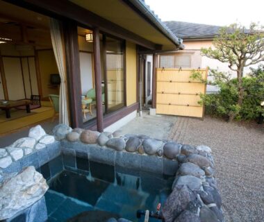 Stone outdoor bath beside tatami room and garden at Onyado Satsuki in Kumamoto