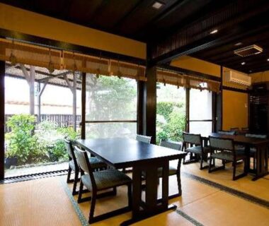 Interior tatami dining space with low wooden tables and garden-facing sliding screens at Onyado Takasago in Saga