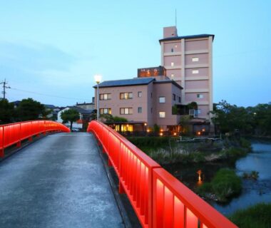 Red bridge over river leading to Onyado Takasago ryokan building in Saga, Kyūshū at dusk